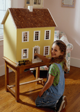 This is a photo of a young girl playing with a dollhouse.