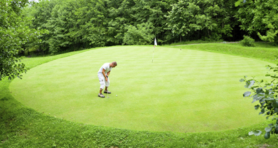 This is a photo of a golfer putting on a circular green.