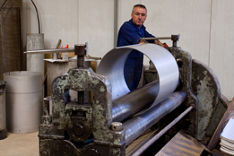 This is a photo of an individual working with sheet metal .