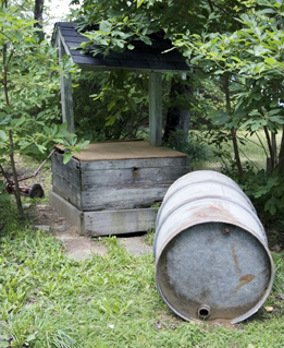 This is a photo of a steel drum located near a well.