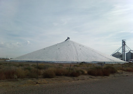 A tarp covers a conical grain pile in this photo.