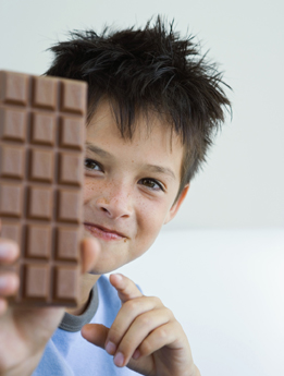 In this photo a boy has a large chocolate bar in his hand. 