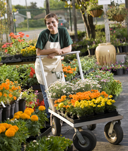This is a photo of a young woman moving a cart of flowers.