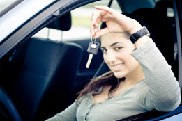 This is a picture of a teenager sitting in a car holding up a key.