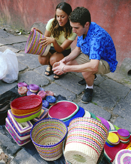This photo shows a young couple looking at colourful baskets from a street vendor.