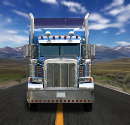 This is an image of a blue transport truck driving down the middle of the road.