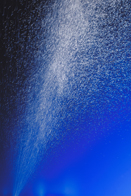 This photograph is of water spraying upward on a blue background.