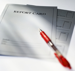 This photograph shows a paper report card with a red pen on it.