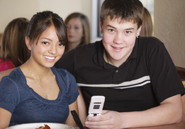 This is a photo of a boy and girl holding a cellphone, possibly reading a text message.