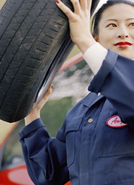This image shows a young woman carrying a tire.