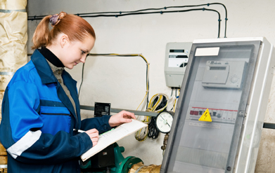 This photograph shows a woman with a clipboard writing numbers down from a meter and chart.