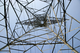 This photograph shows a powerline tower from the ground looking skyward.