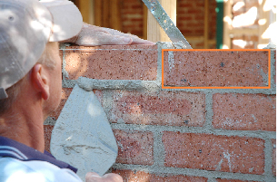 This photograph is of a bricklayer building a wall with a quadrilateral outlined in orange.