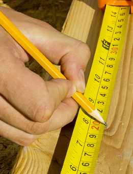 This photograph shows a tape measure along with a pencil in hand.