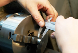 This is a photograph of a vernier caliper being used to measure the length of a metal shaft.