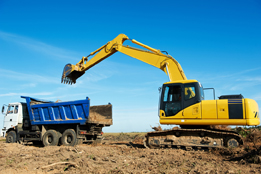 This photograph shows an excavator loader at work loading a dump truck.