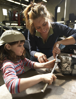This photograph is of a mechanic assembling a part with her young daughter.