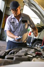This photo shows a mechanic checking an engine oil dipstick.
