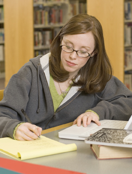 This photograph shows a young woman doing research at a library.