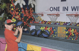 This is a picture of a boy playing a basketball game at a carnival.