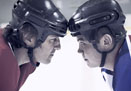 This is a photo of two hockey players staring each other down in the face-off circle.