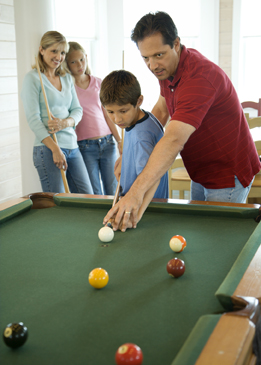 The photo shows a family playing pocket billiards.