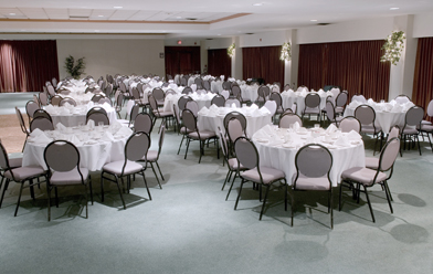 This picture shows a hall with tables surrounded by chairs.