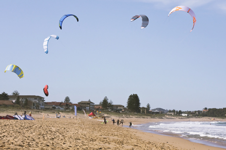 This shows a picture of kite surfing at a beach.