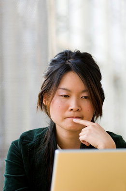 This is a picture of a young Asian student working on a laptop computer.