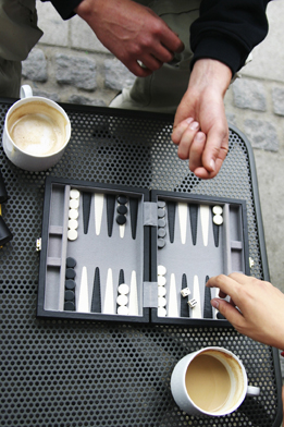 This is a picture of a backgammon board. Two people are playing the game and drinking coffee.