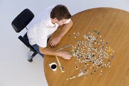 This photo shows a high-angle view of a man working on a jigsaw puzzle.
