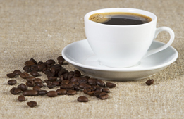 This is a photo of a cup of coffee with coffee beans beside it.