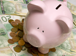 This is a photo of a piggy bank on top of a pile of pennies and 20-dollar bills.