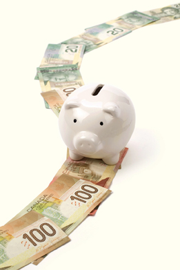 This photo shows a piggy bank standing on a trail of bills of various denominations.