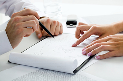 This is a photo of two people reviewing a plan in a notebook.