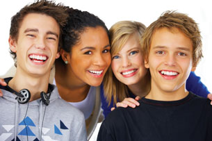 This photo shows a diverse group of smiling young adults, composed of two males and two females.