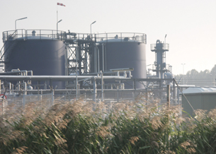 This photo is of a biorefinery with a field of barley in front of it.