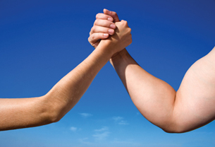 This photo is of two arms in an arm-wrestling pose. One arm is skinny, while one arm is muscular.