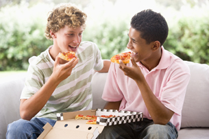 A dark-haired woman is eating a slice of pepperoni pizza.