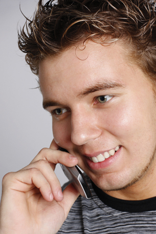 A photograph of a young man talking on a cellular telephone.