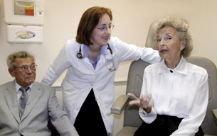 A photograph of a doctor talking with an elderly couple.