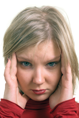 This photograph shows a young blonde woman holding her fingers to her temples as if she has a headache.