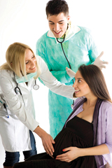 The photo shows healthcare professionals talking to a woman who is near the end of her pregnancy 
