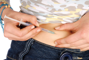 This photograph shows only the middle abdominal area of a female who has lifter her shirt a bit to inject herself with insulin in the abdominal area. Insulin must be injected rather than taken orally because the digestive enzymes would digest it before it could be absorbed. Development of insulin nose sprays is being pursued.