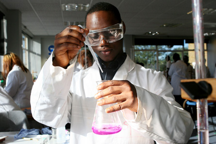 A male teenage science student is using equipment to do a lab.