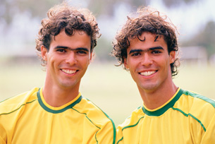 This photograph shows monozygotic male twins, who appear to be in their early twenties. Both have dark, curly hair, dark eyes, heavy eyebrows, and other similar facial features.
