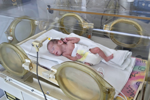 This photograph shows a newborn baby in an incubator.