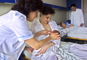 This photograph shows a mother being helped to nurse her newborn baby.