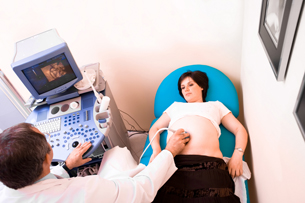 This photograph shows an obstetrician performing a 4-D ultrasonic scan on a pregnant woman.