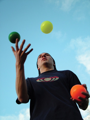 A photo shows a young man juggling three balls.